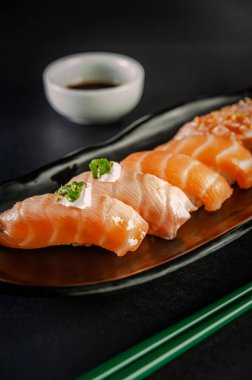 Salmon onigiri varieties. Blowtorcherd salmon onigiri and salmon onigiri with shoyu and chopsticks on a black background.