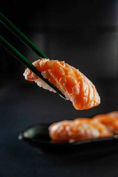 Truffle salmon onigiri on chopsticks with salmon onigiri varieties on a background.