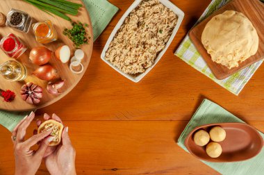 Kadın elleri ahşap mutfak masasında Brezilya kroketi (coxinha de frango) hazırlıyor.