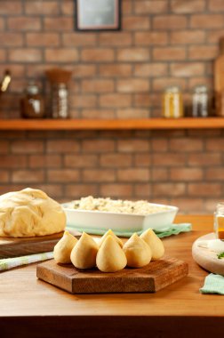 Brezilya chiken kroketi (coxinha de frango) ahşap bir masa ve tuğla mutfak arka planında.