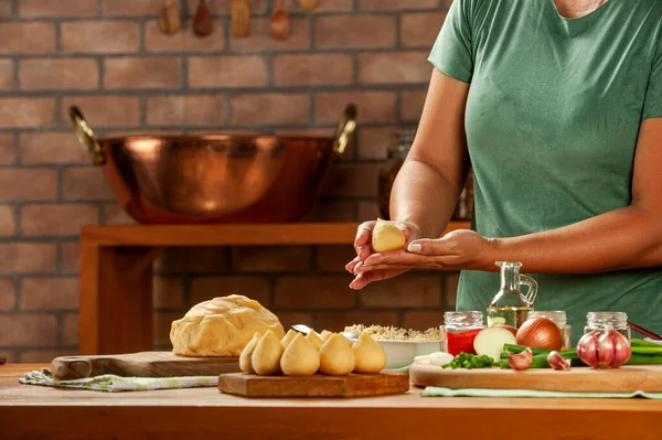 Kadın elleri tahtadan bir masada Brezilya kroketi (coxinha de frango) hazırlıyor..