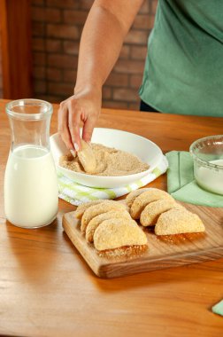 Tahta bir masada Brezilya usulü ekmek doldurulmuş kroket (risolis de carne) yiyen kadın. Üst görünüm.