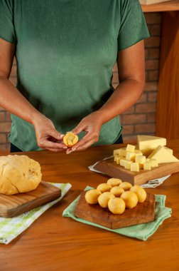 Brezilya peyniri doldurulmuş kroket hazırlayan kadın (Bolinha de queijo) ahşap bir masada..