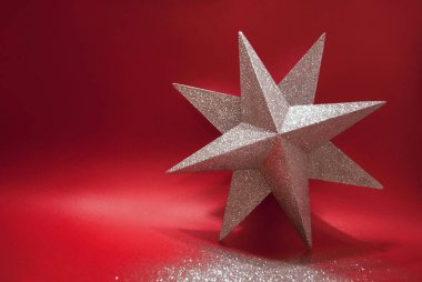 Kırmızı arka planda gümüş parıltı yıldızı. Kış tatili teması. Yeni yıl ya da Noel konsepti. Metin için boşluk