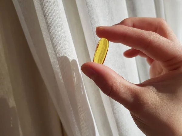 Close up a women hand holding fish oil capsule. Healthy life concept