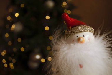 Arka planda kırmızı şapkalı bir kardan adam bulanık ışıklar Noel ağacı, arka planda Bokeh ile bulanık. Noel 'i ve yeni yılı kutluyoruz. Kış tatili teması. Metin için boşluk