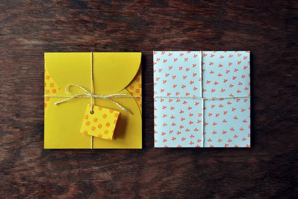 Sarı, beyaz zarf ahşap masanın üzerinde elle yapılmış. Düz yatış, üst görünüm