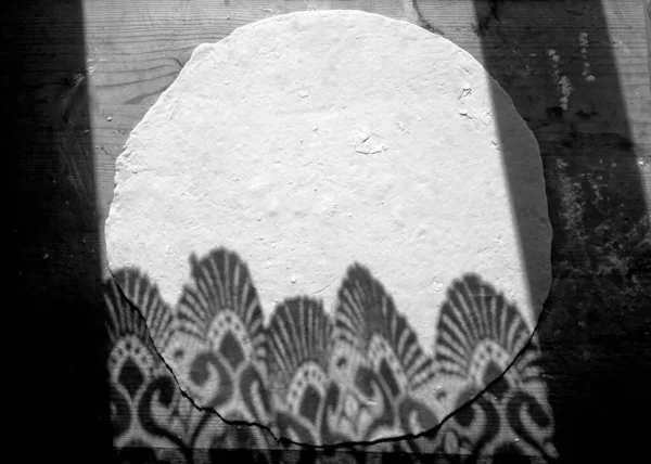 Rolled dough on a wooden surface, top view. The shadow of an openwork curtain on a rolled dough. Light and shadow