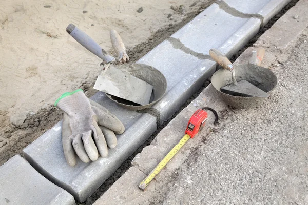 Baustelle, Bordstein und Maurerwerkzeuge — Stockfoto