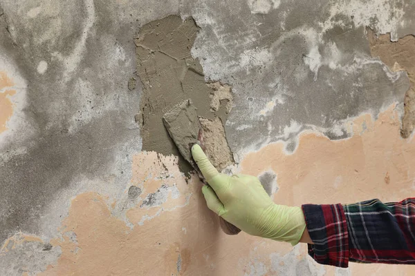 工人用铲子固定墙体裂缝和损坏 铺石膏 图库图片