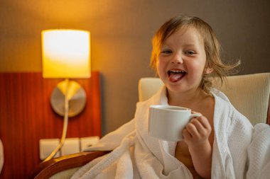 Yatak odasında çay içen küçük tatlı bir kızın portresi..