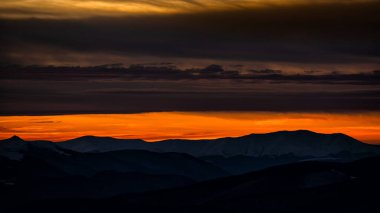 Dağların siluetleri üzerinde renkli bir kış gökyüzü. Bieszczady Dağı, Karpatlar, Polonya.