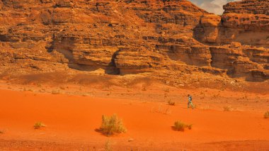 Küçük kızıyla birlikte çölde yürüyen bir bebek taşıyıcısının içinde güzel bir anne. Wadi Rum, Ürdün.