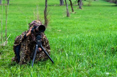 Bir kadın doğa fotoğrafçısı bir hayvanı bekliyor..