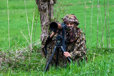 Bir kadın doğa fotoğrafçısı bir hayvanı bekliyor..