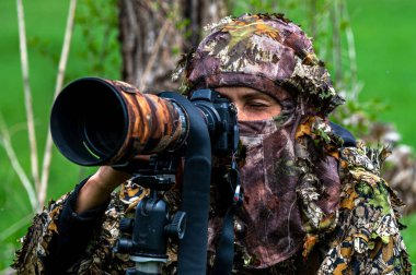 Bir kadın doğa fotoğrafçısı bir hayvanı bekliyor..