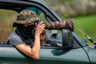 Female paparazzi detective taking pictures from the hide.