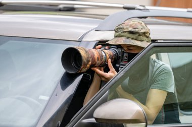Female paparazzi detective taking pictures from the hide.