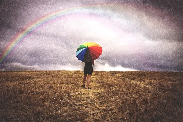 Woman in field with colorful umbrella in the rain — Stock Photo, Image
