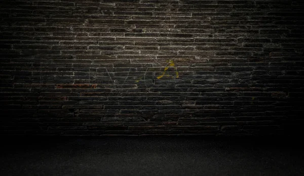 黒いアスファルトの床の上に汚い暗いレンガの壁 — ストック写真