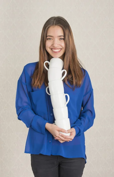 Attractive young woman balancing a pile of cups — Stock Photo, Image