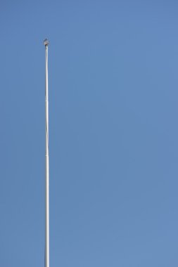 Flagpole without flag and a clear blue sky clipart