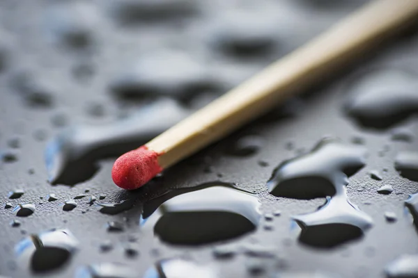 Dry match and raindrops on black metal surface — Stock Photo, Image