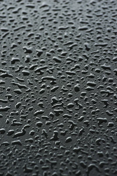 Raindrops on black metal surface — Stock Photo, Image