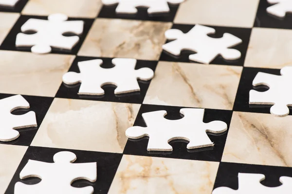 Blank puzzle pieces on chess board — Stock Photo, Image