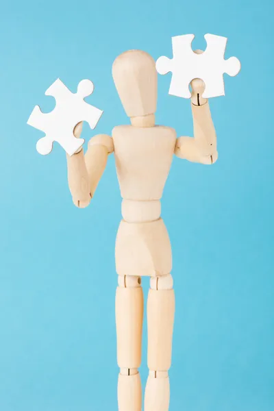 Human figurine hold white puzzle pieces — Stock Photo, Image