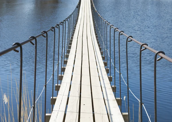 Подвесный мост через реку в яркий солнечный день — стоковое фото