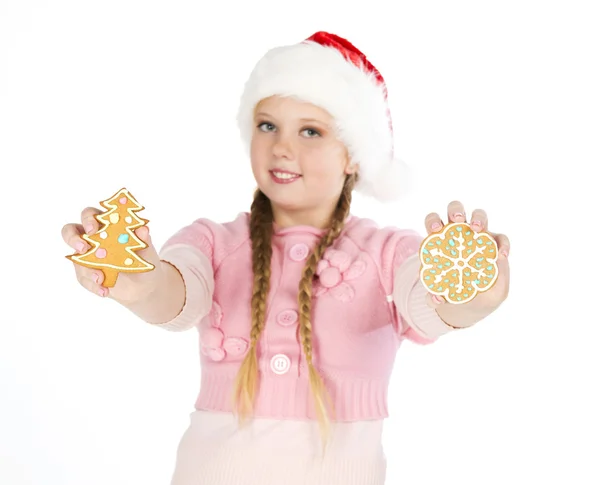 Mädchen mit roter Weihnachtsmütze hält Lebkuchen in der Hand — Stockfoto