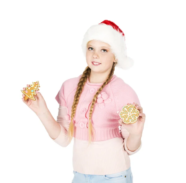 Girl in red christmas hat holds gingerbread cookies in hand on w — Stock Photo, Image