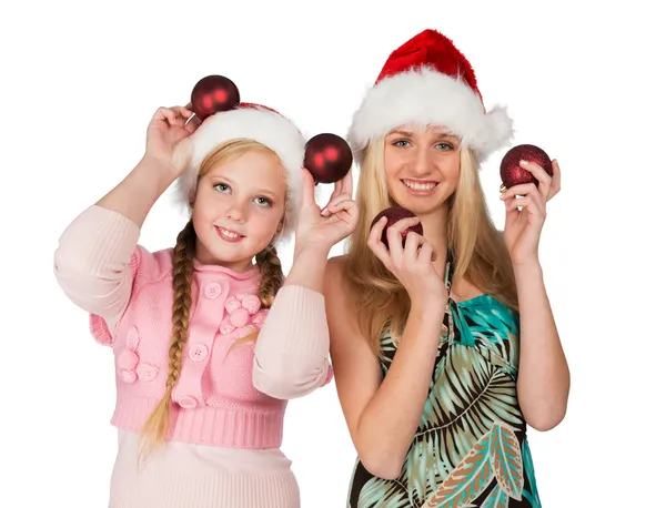 Two girls in red christmas hats hold red fir-tree spheres in han — Stock Photo, Image