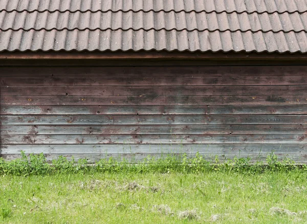 Staré hnědé dřevěné zdi s zelené trávy jako pozadí — Stock fotografie