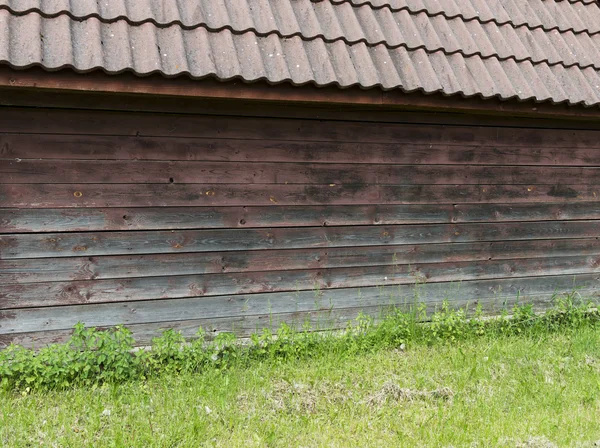 पार्श्वभूमी म्हणून हिरव्या गवत जुनी तपकिरी लाकडी भिंत — स्टॉक फोटो, इमेज