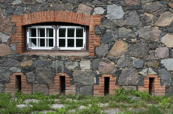 Muro da pietre di granito con una finestra e la strada vecchia overgr — Foto Stock