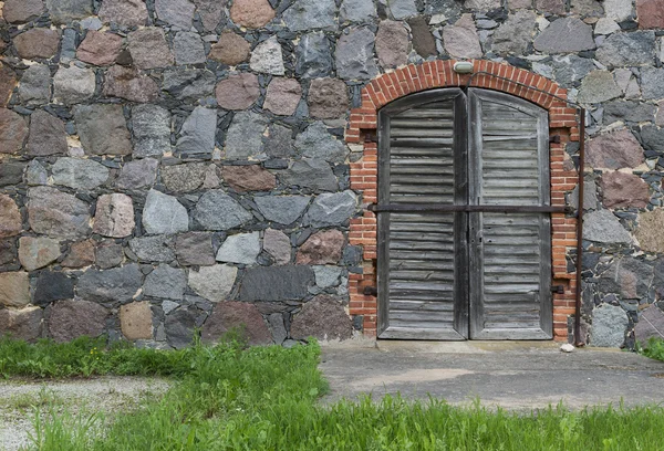 Muro da pietre di granito con una porta e la vecchia strada asfaltata o — Foto Stock