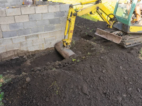 Tractor cava una zanja alrededor del edificio, una zanja para un pavimento Fotos de stock