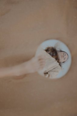 Kumsalda aynayla poz veren bej elbiseli güzel bir esmer.