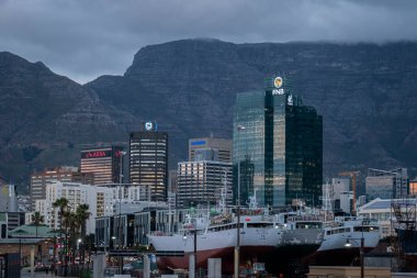 Alacakaranlıkta, Cape Town, Güney Afrika 'da ön planda gemileri ve binaları olan Masa Dağı.
