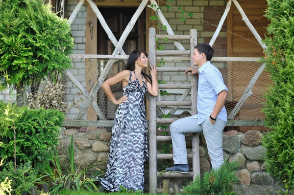 Young beautiful couple standing near a ladder in a village and s — Stock Photo, Image