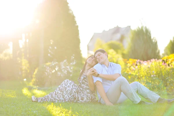 Junges glückliches Paar, das Rücken an Rücken zueinander sitzt - hell — Stockfoto