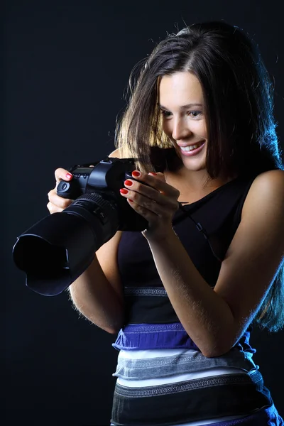 Kvinna med kameran på en mörk bakgrund ser på hennes bra skott — Stockfoto