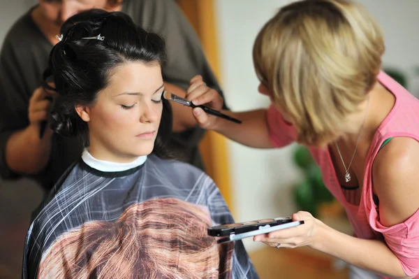 Young beautiful bride applying wedding make-up by make-up artist — Stock Photo, Image