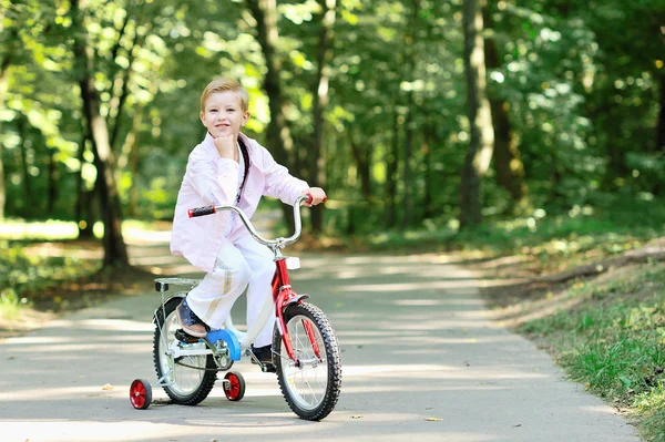 Retrato de menino bonito em uma bicicleta sorrindo e descansando seu queixo o — Fotografia de Stock