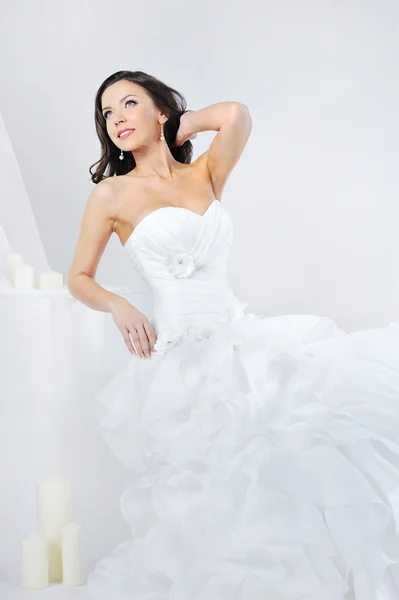 Schöne lächelnde Mädchen in einem weißen Hochzeitskleid auf weißem Hintergrund — Stockfoto