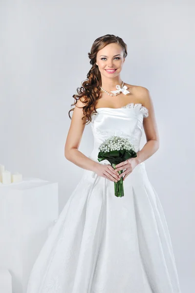 Menina sorridente bonita em um vestido de noiva branco em um backg branco — Fotografia de Stock
