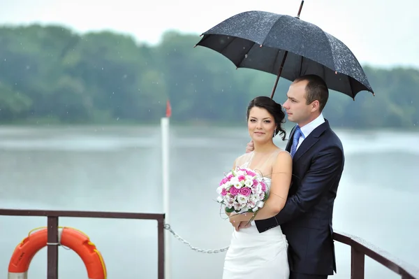 Bride and groom in a rainy weather on a boat — Stock Photo, Image