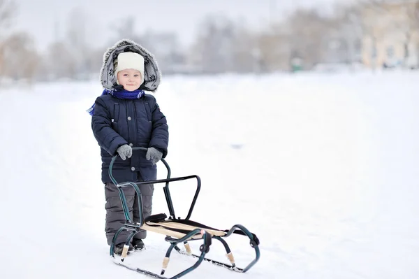 Мальчик с санями зимой — стоковое фото